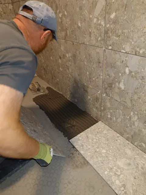 Damion laying porcelain floor tiles in a freshly tiled bathroom