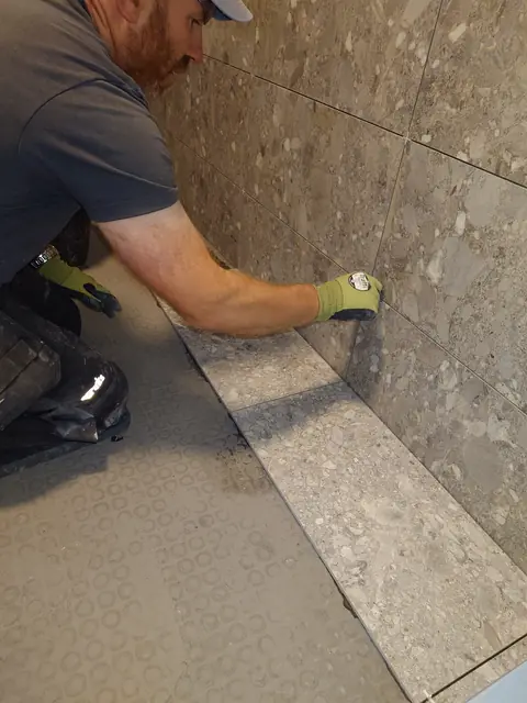 Pressing a floor tile down and checking it against the row