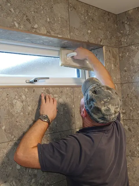 Grouting the tiled window reveal, sill pitched back into the room
