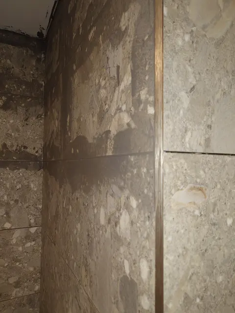 Grey terrazzo-effect porcelain wall tiles lined through an internal corner