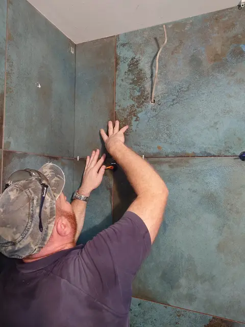 Pressing a large format metal-effect tile into the adhesive